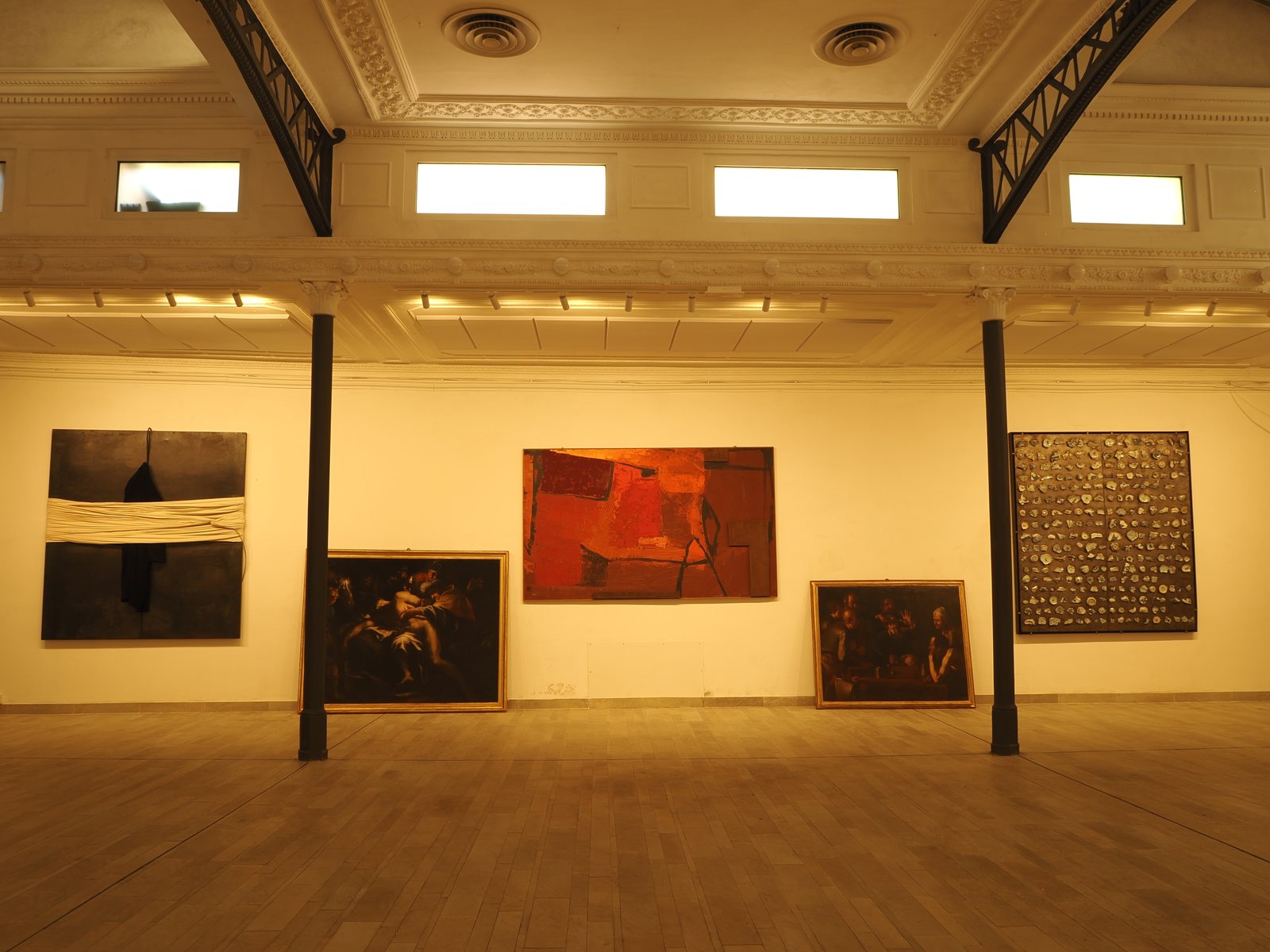 Studio Liberty — parete espositiva con opere contemporanee e dipinti appoggiati a terra, spazio per mostre a Roma centro